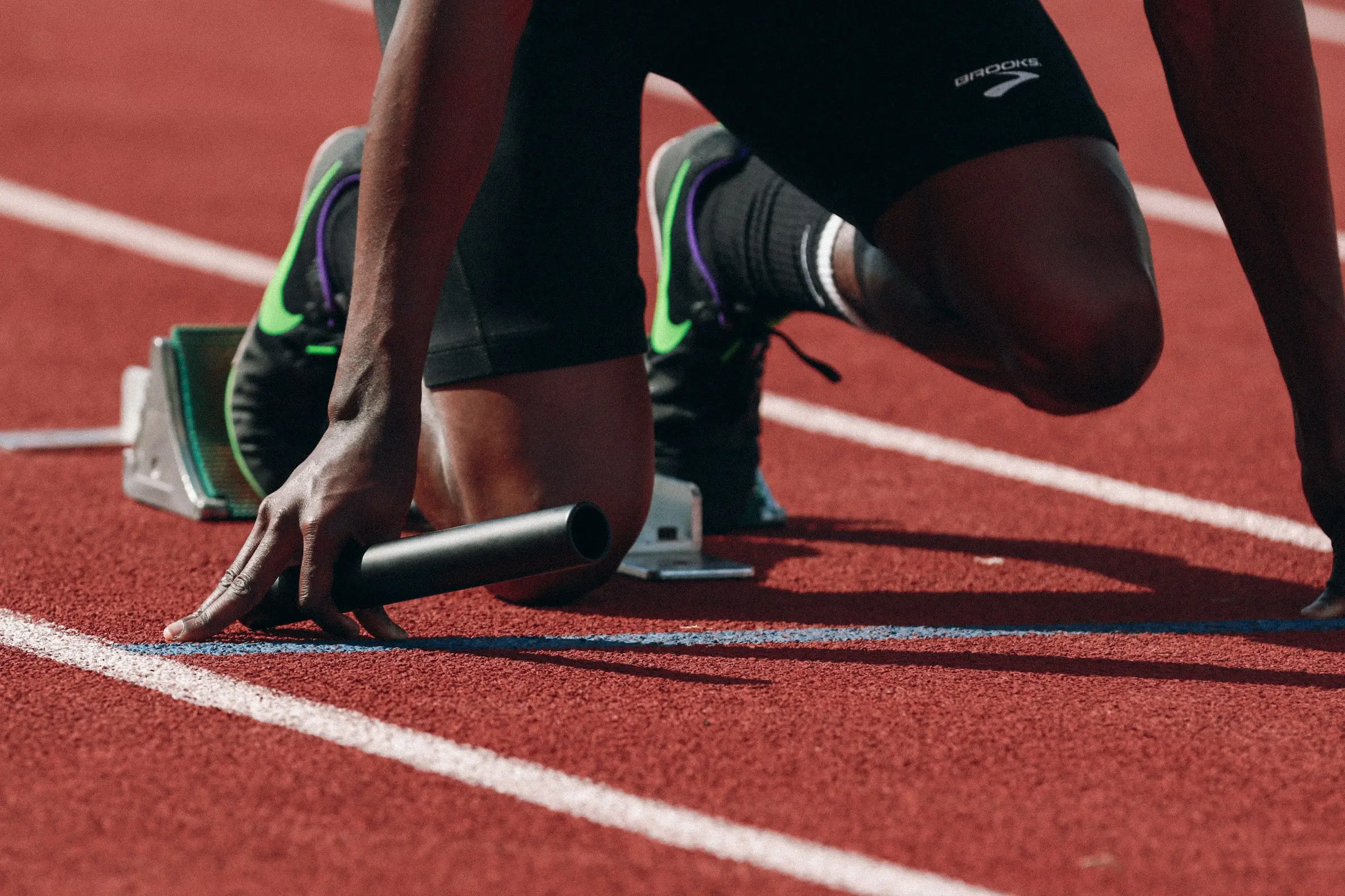 A sprinter set in the blocks on a red running track