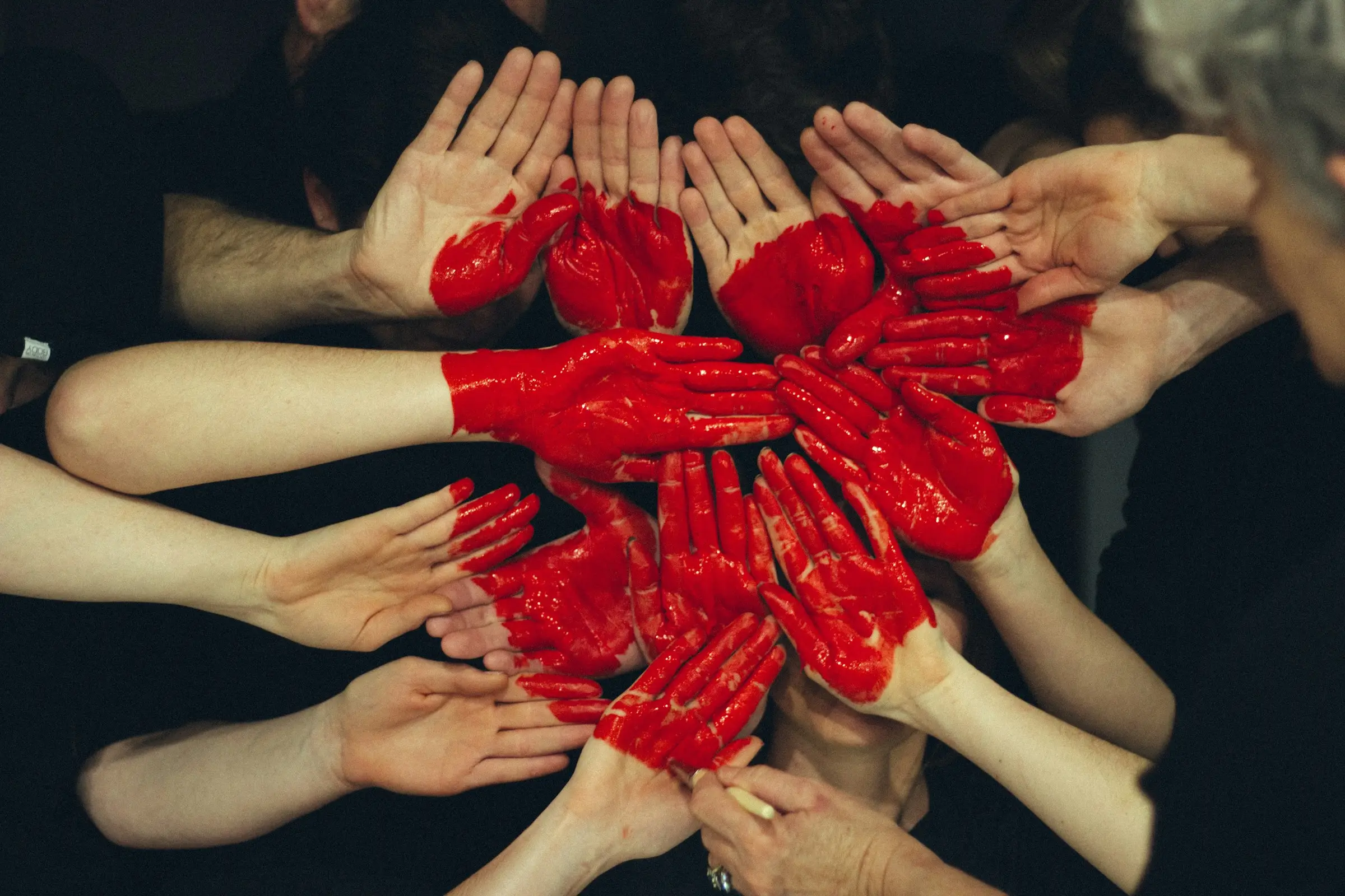 Many hands painted red, joined together into a heart