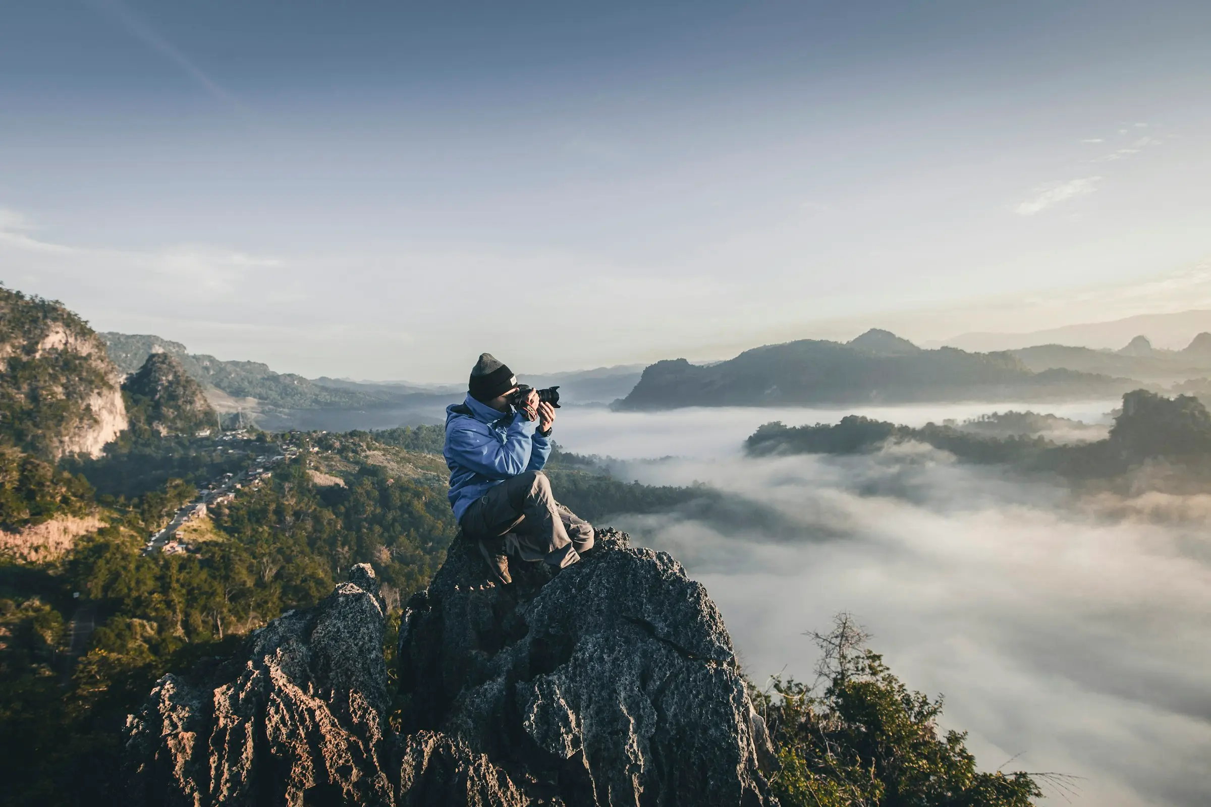A photographer shooting from a mountain ridge above morning fog
