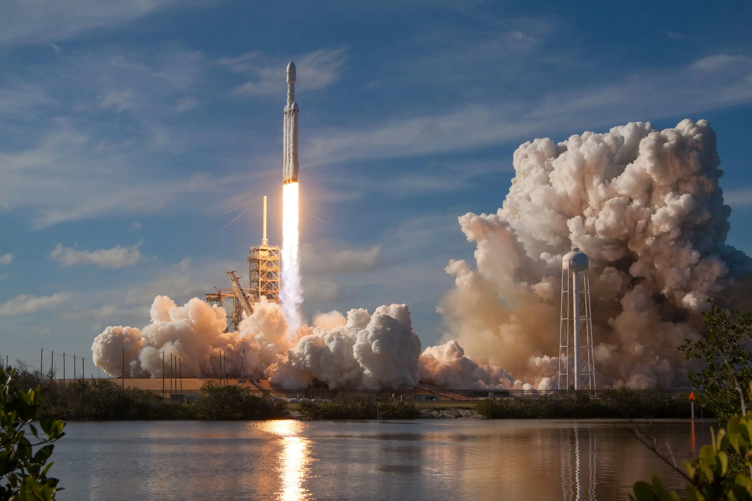 A rocket lifting off its pad at dawn, exhaust lit from below